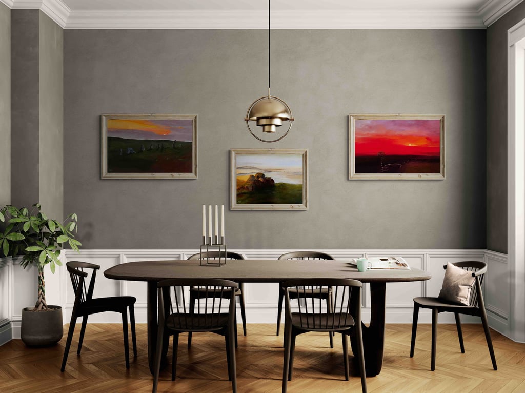 Modern dining room with a dark wood table, gold pendant light, and paintings on grey walls.