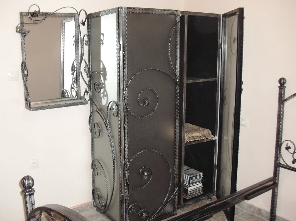 Handcrafted wrought iron wardrobe with intricate scrollwork and matching wall mirror.