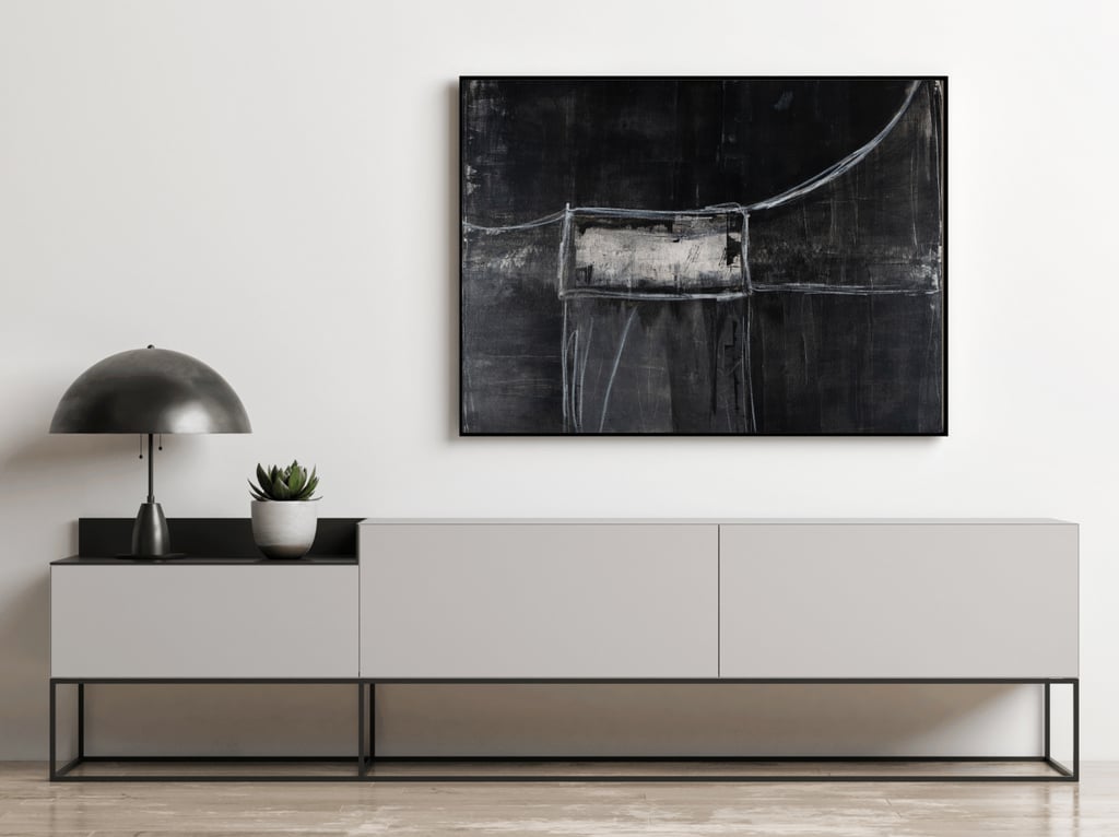 Black abstract wall art hanging above a modern white sideboard with a minimalist metal lamp.