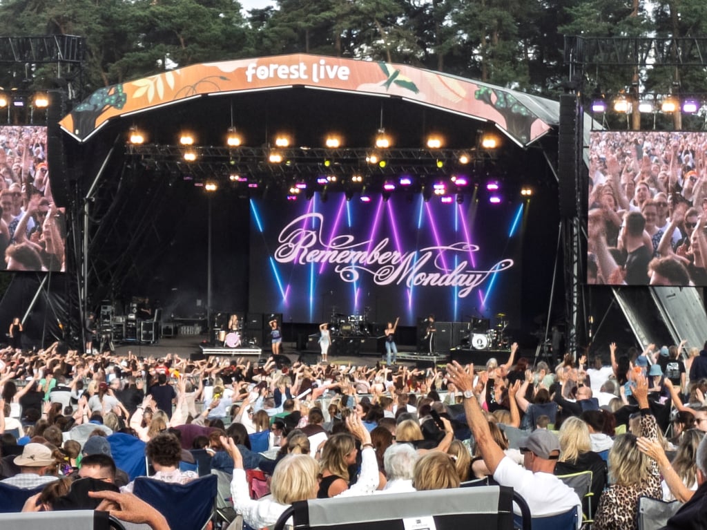 Crowd at a Forest Live outdoor music festival watching Remember Monday perform on a large stage.