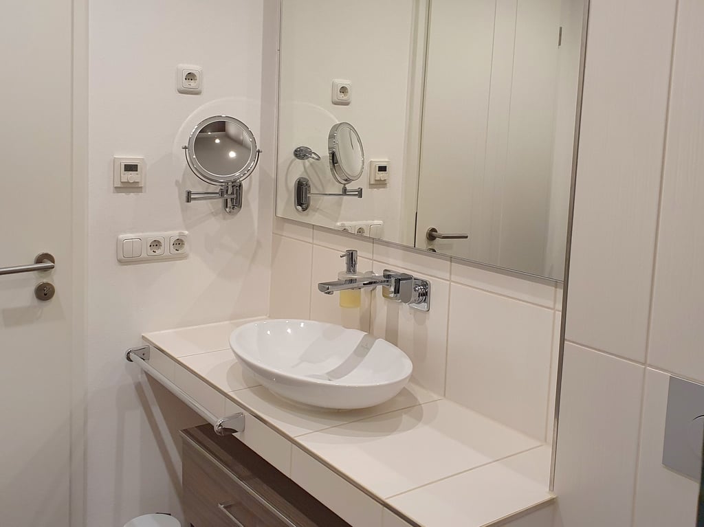 Das Bad mit Waschbecken, Schrank und Kosmetikspiegel