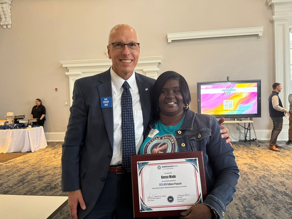 Kenya Wade smiling while receiving her 2025 HER Fellows Program certificate award from a colleague.