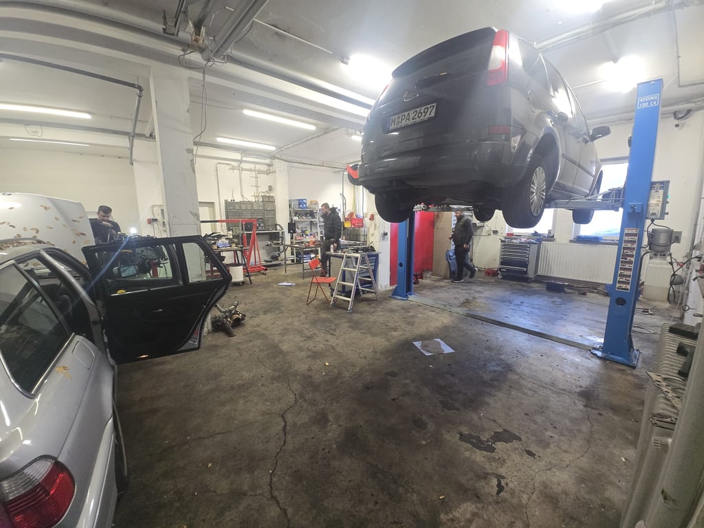 Auto wird in der KFZ-Werkstatt mit einer Hebebühne für Inspektion oder Reparaturen angehoben.