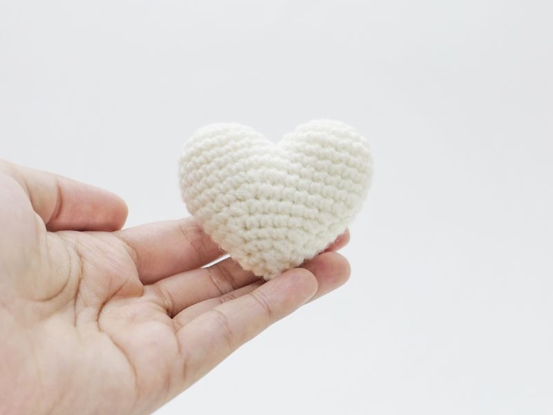 Mano sosteniendo un corazón de crochet color blanco