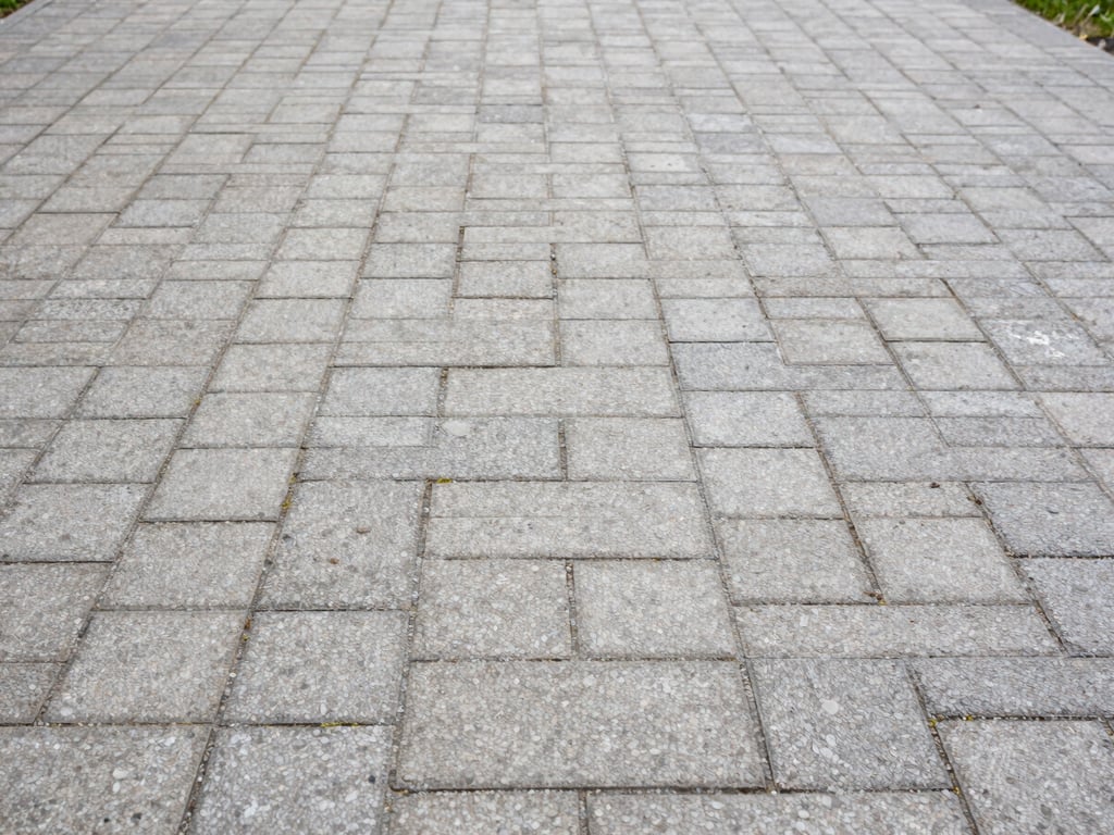 Same stone pavement at German residential property after pressure washing, joints clean and pale, surface dry and uniform, overcast daylight showing crisp restored texture
