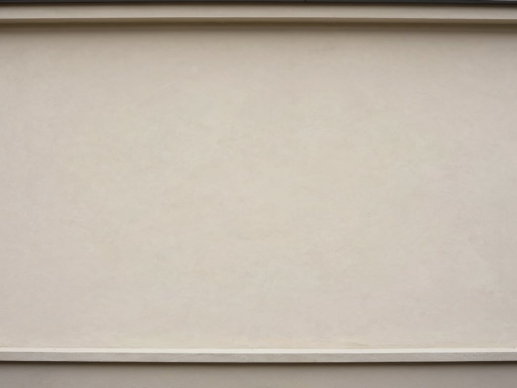 Same building facade after professional cleaning, rendered plaster surface restored to original light tone, overcast daylight showing uniform clean finish across full wall