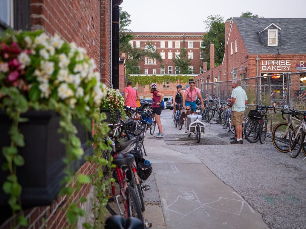 People on and near a large group of bikes downtown in an alley