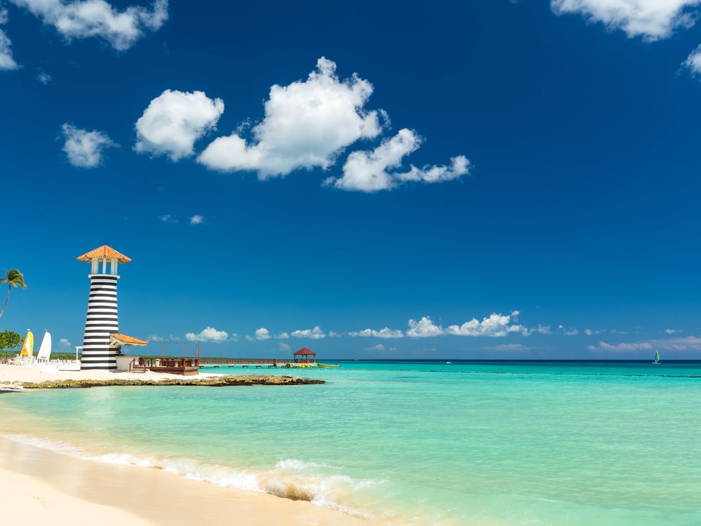 Scenic beach with turquoise water and striped lighthouse in Bayahibe, Dominican Republic