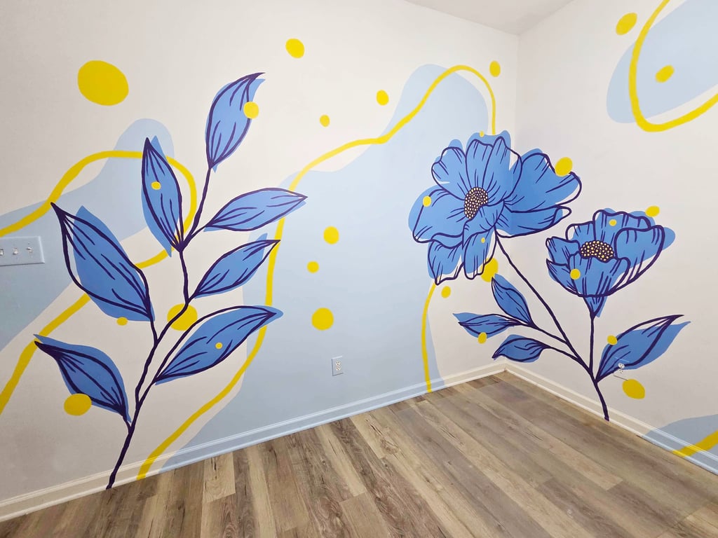 Modern floral wall mural with blue flowers, yellow accents, and abstract shapes in a room with wood floors.