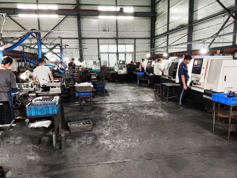 Operators working at industrial CNC machines and lathes in a manufacturing factory workshop.