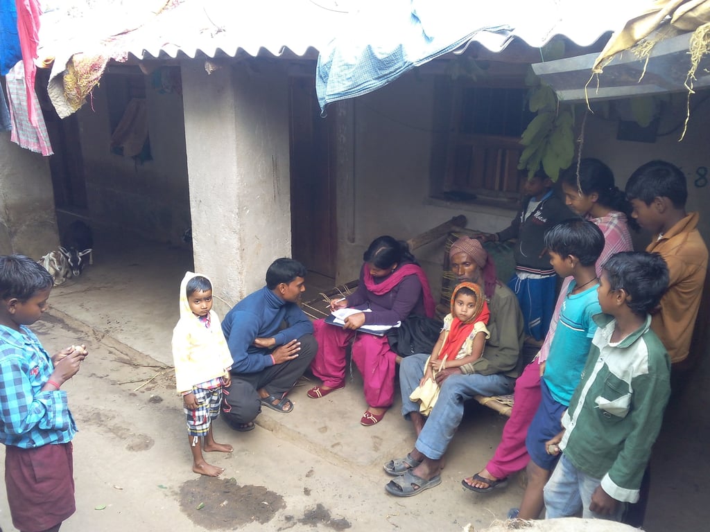 A community health worker interviews a rural family in India to collect survey data.