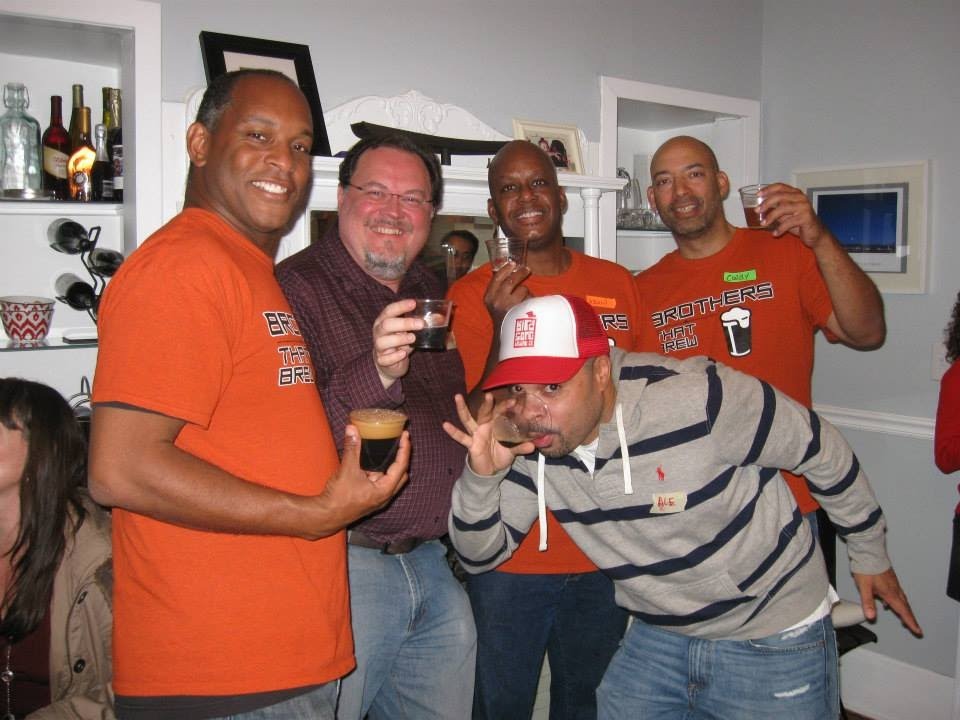 A group of friends smiling and drinking craft beer at a home tasting event.