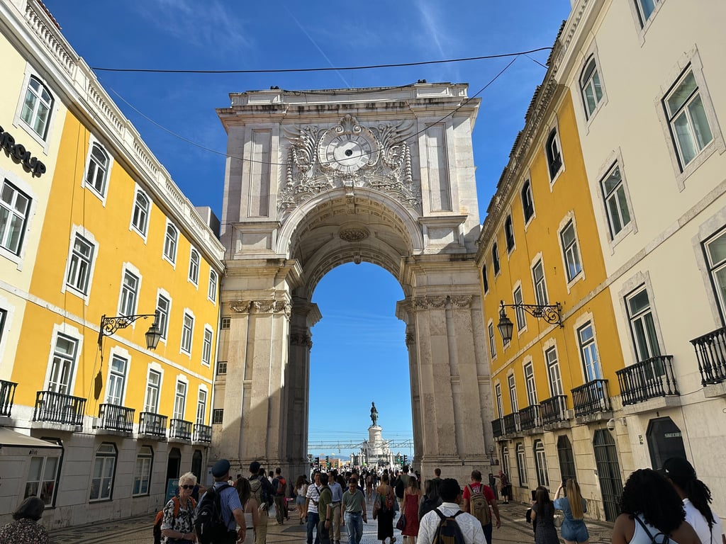 Duas paredes amarelas, conectadas por um arco de concreto que conta com uma escultura no topo 