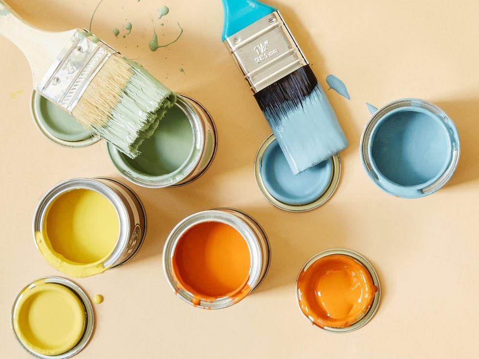 Ekologiczne farby w pastelowych kolorach. Otwarte puszki gotowe do malowania a na nich pędzle