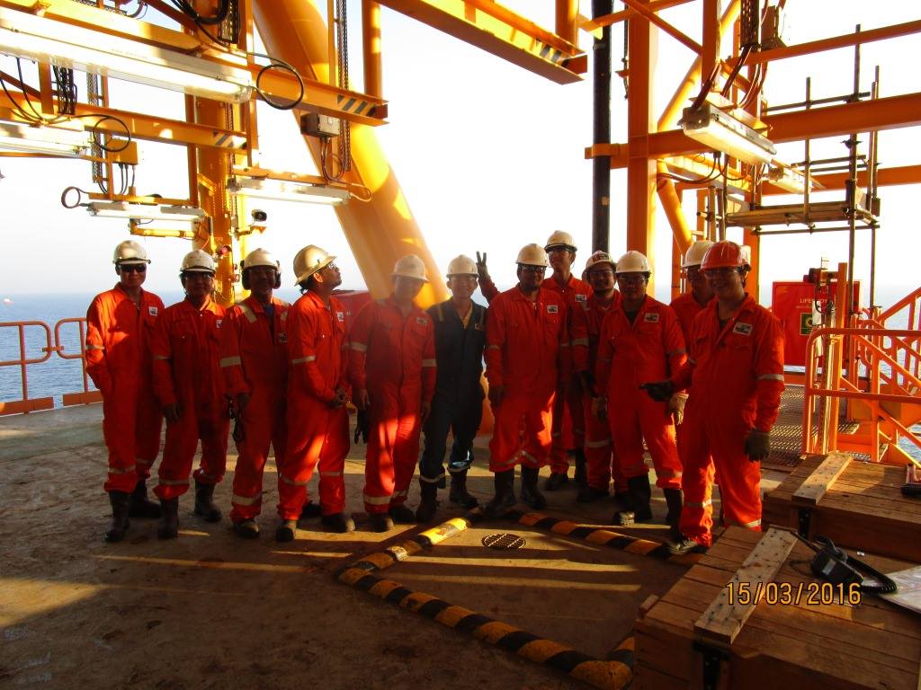 Offshore oil rig workers hard hats posing on a platform.