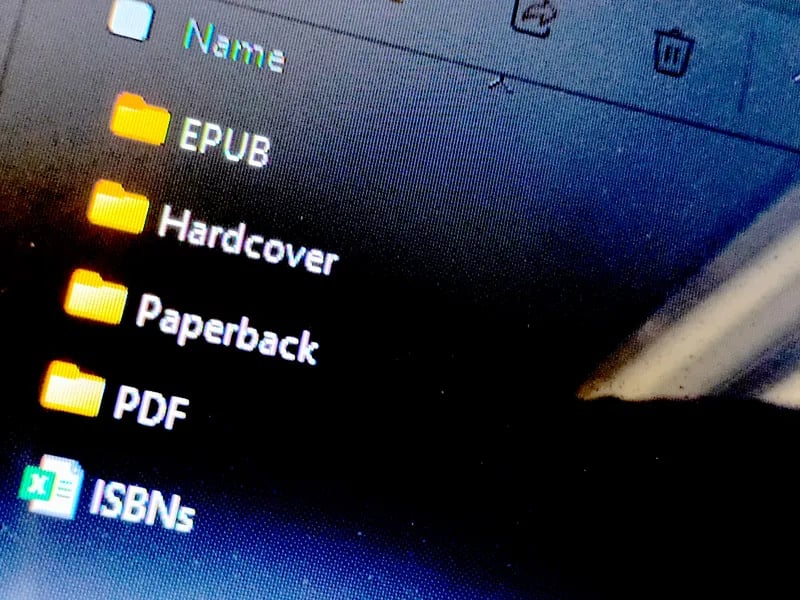 Close-up of a computer screen showing folders labeled EPUB, Hardcover, Paperback, and PDF