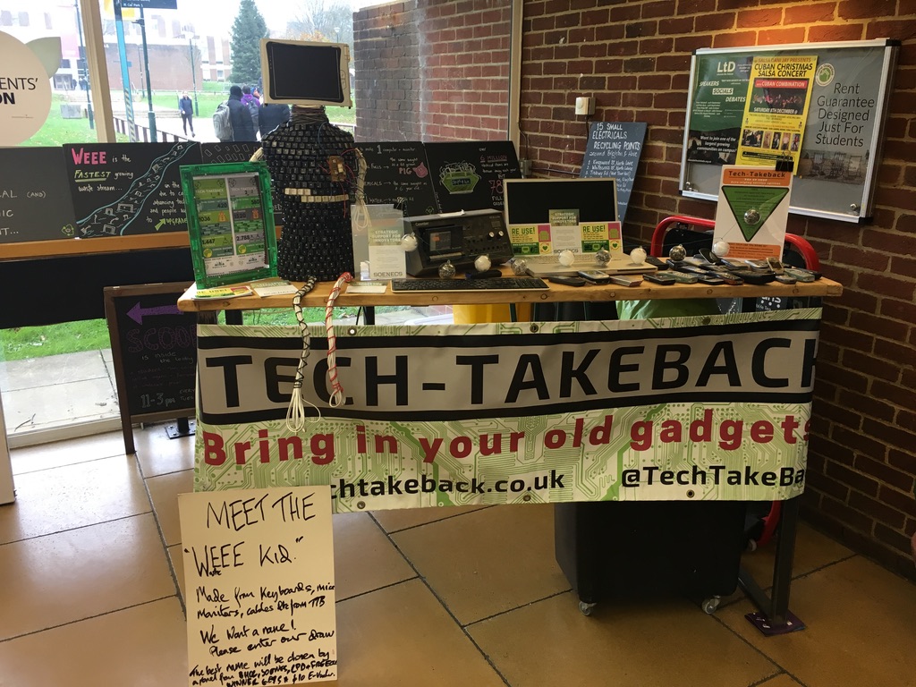 Tech-Takeback's first event. Old tech sits on a table with a homemade Tech-Takeback banner.