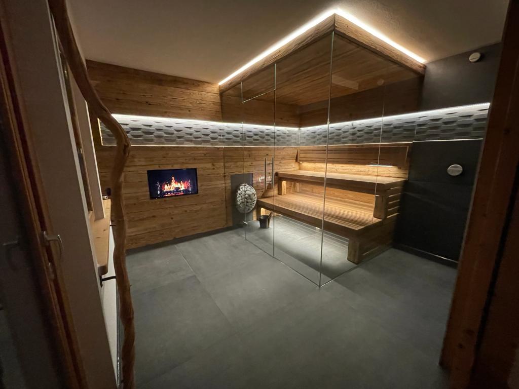 Moderne Innensauna mit Eckverglasung, ausgestattet mit rustikaler Holzverkleidung und indirekter LED-Deckenbeleuchtung