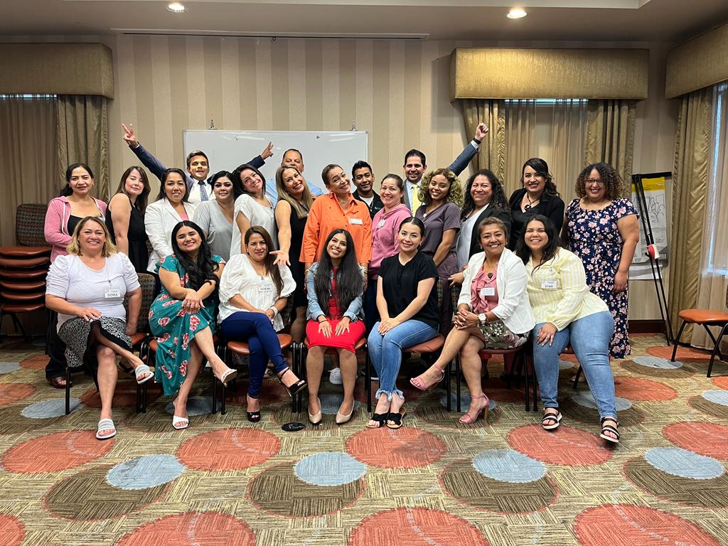 A diverse group of smiling professionals posing for a corporate team building photo in a conference room.