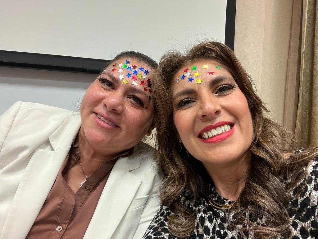 Two smiling women with colorful star stickers on their foreheads posing for a close-up portrait.