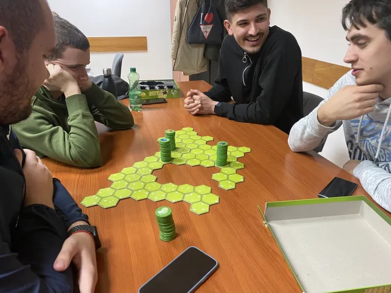 Grupa ljudi igra društvenu igru Battle Sheep, uživajući u strateškoj zabavi na stolu