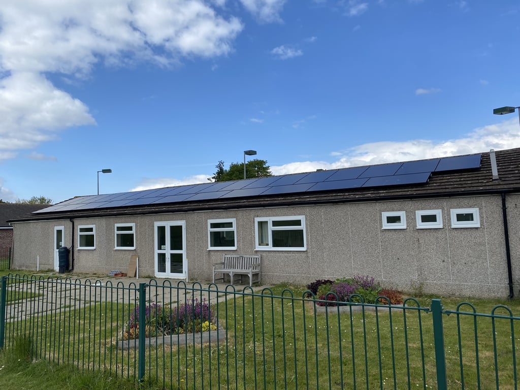 Elsenham Memorial Hall in Elsenham, exterior view with entrance doors, windows, bench seating and solar panels on the roof.