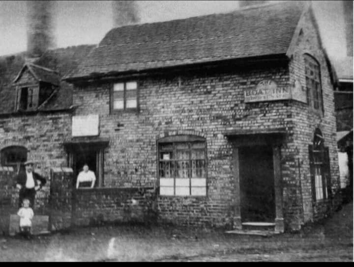 Vintage black and white photo of the historic Boat Inn brick pub with people standing outside.