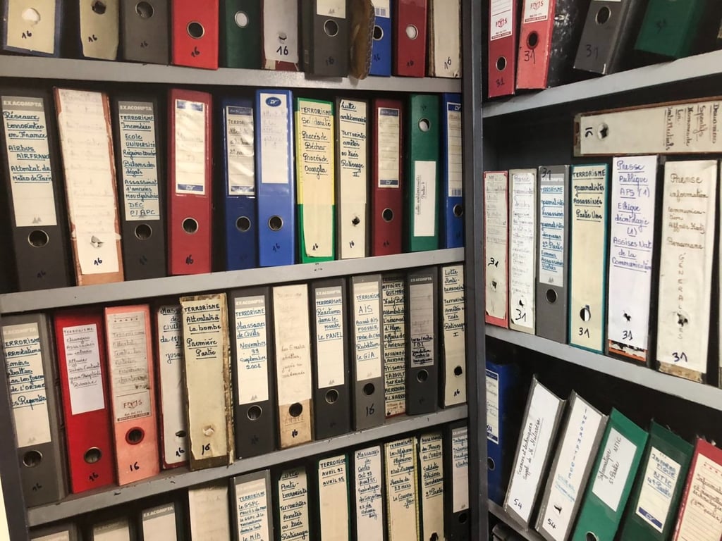 Rows of colorful lever arch ring binder folders on shelves containing organized archive documents and 
