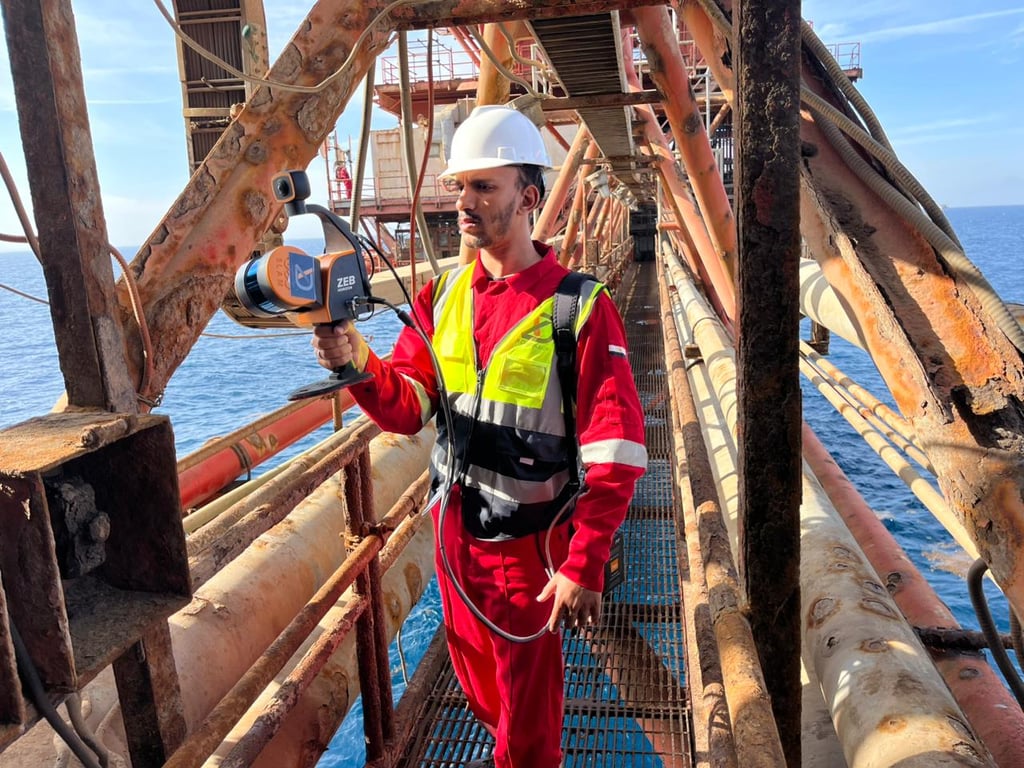 Engineer using a handheld ZEB Horizon SLAM laser scanner for 3D mapping on an offshore oil platform.