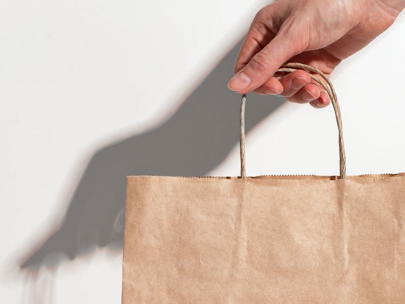 une main qui tend un sac en papier kraft