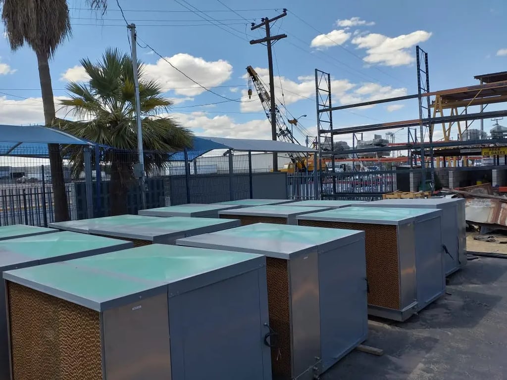 Enfriadores evaporativos industriales alineados en el patio de una maquiladora