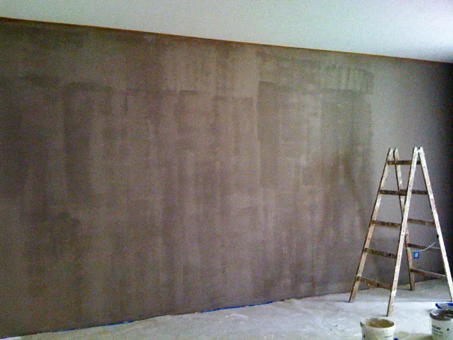 Taupe-coloured wall prepared for decoration with hand-painted art, a dropcloth and ladder