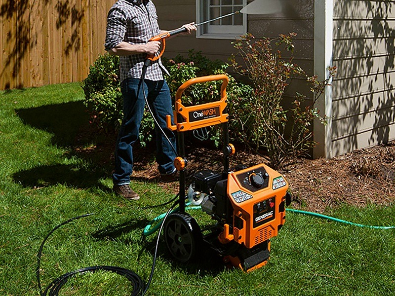 man using a pressure washer to clean a house