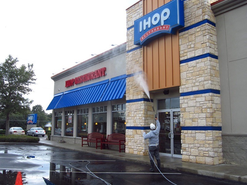 pressure washing services worker pressure and soft wash cleaning of commercial restaurant 