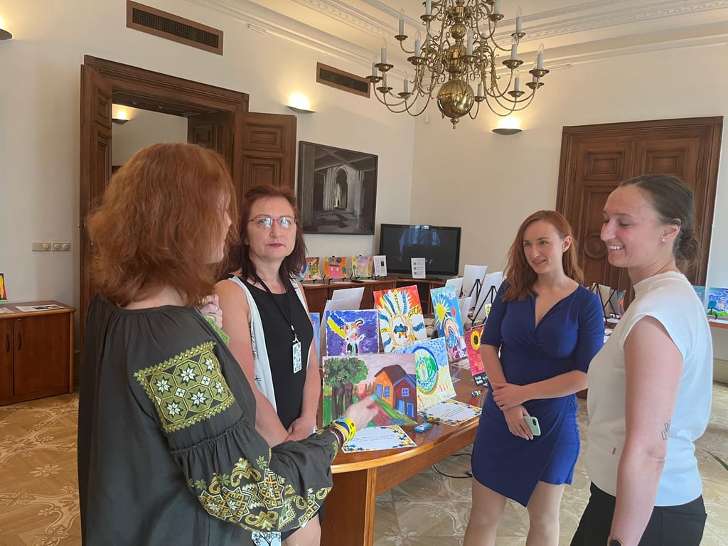 People discussing the exhibit of paintings by kids displaced by war