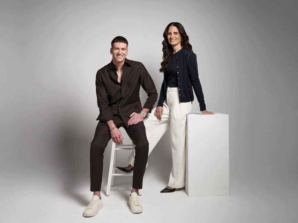 Professional studio portrait of a man and woman in business casual attire posing against a grey backdrop.