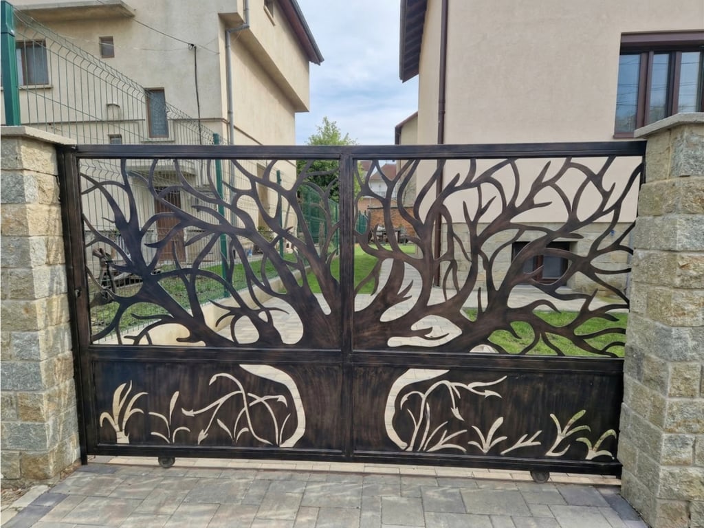 Custom decorative laser-cut metal driveway gate featuring a spreading tree design and stone pillars.