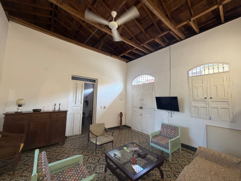 Rustic living room with high vaulted wooden ceilings, patterned tile floors, and colonial-style furniture.