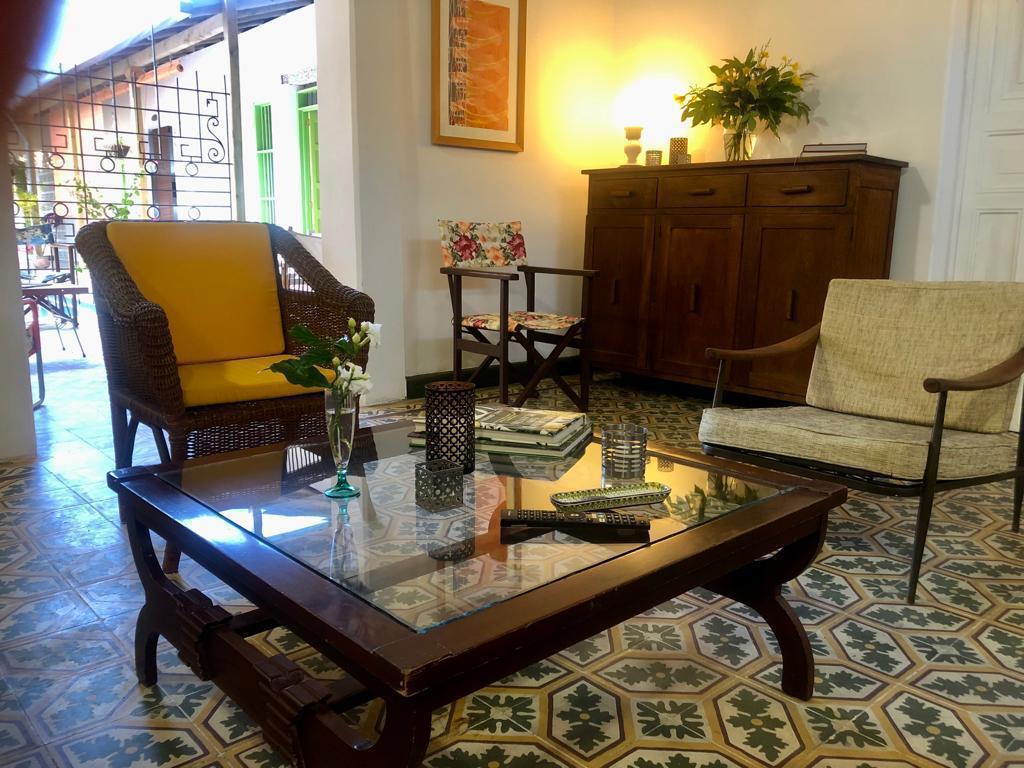 Rustic living room with vintage chairs, glass coffee table, and patterned tile floor.