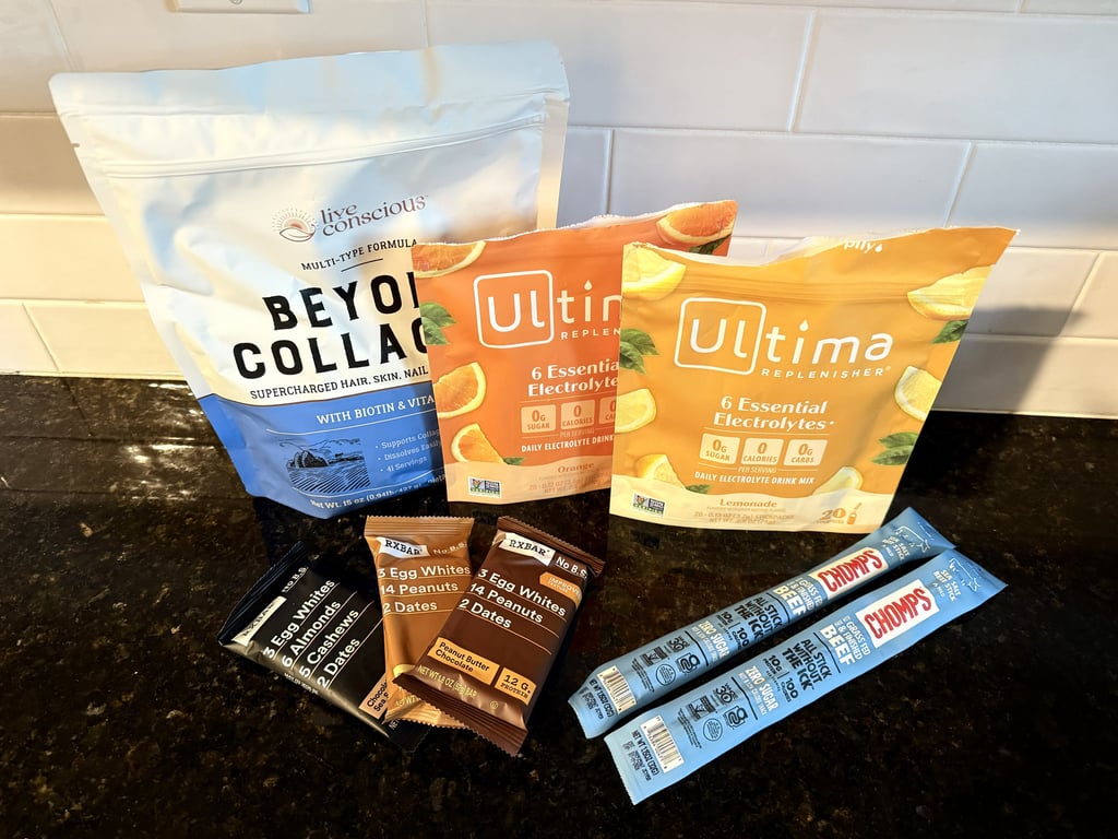 Collagen, protein snacks, RXBARs, beef sticks, and electrolytes arranged on the kitchen counter