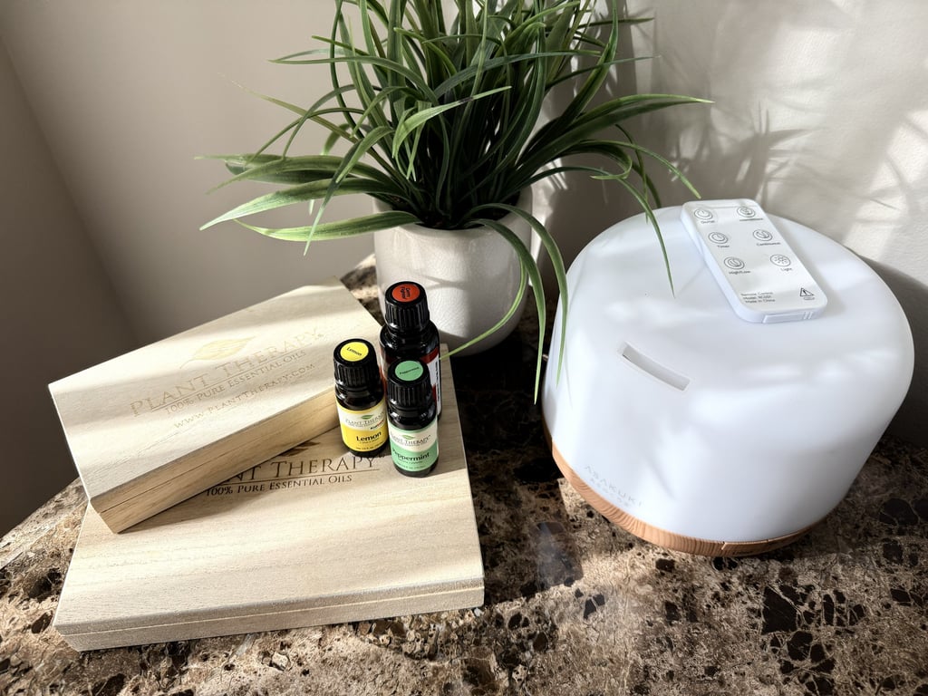 Essential oil diffuser with oils on a nightstand beside a green plant creating calm bedtime setting