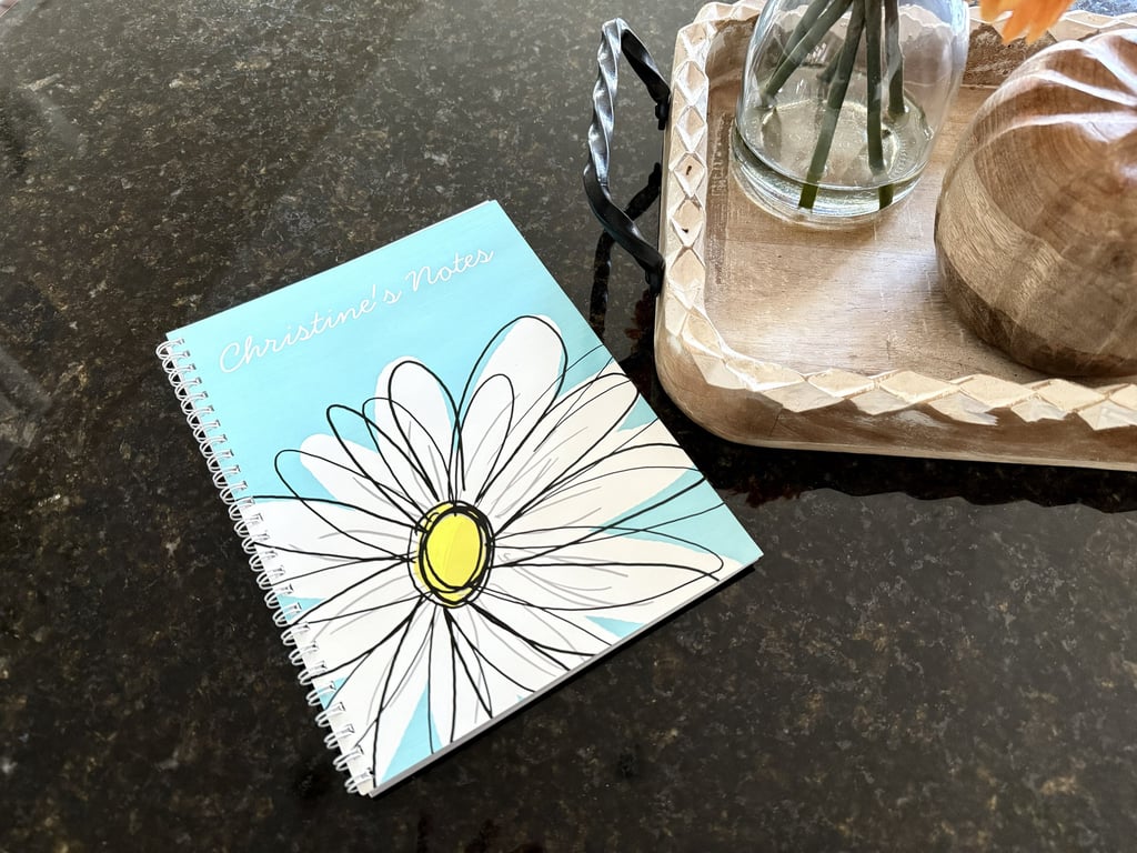 Personalized notebook on a kitchen island with a flower and small pumpkin beside it