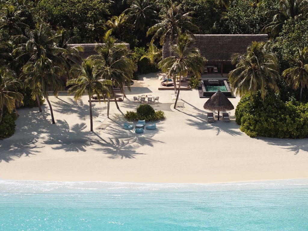 a beach with a beach chair and palm trees, One and Only Reethi Rah
