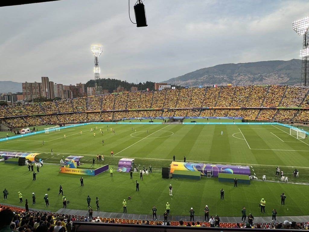 Estádio Atanasio Girardot em Medellín iluminado durante partida noturna com arquibancadas cheias.
