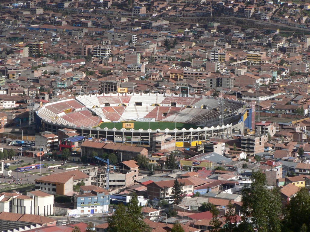 Estádio Inca Garcilaso de la Vega em Cusco, no Peru, com vista ampla das arquibancadas e gramado em dia de céu claro.