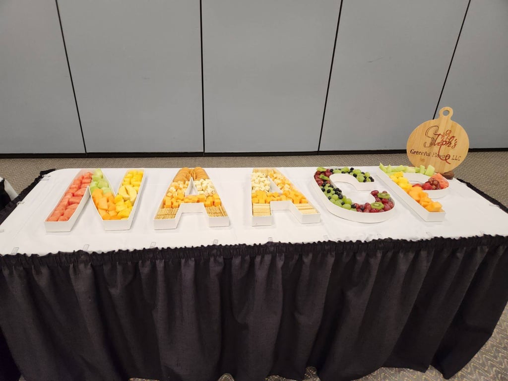 Fruit and cracker catering platter spelling NAACP in letter-shaped serving dishes on a table.