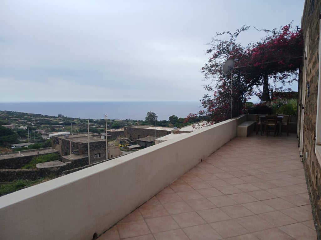 Panoramic terrace of dammuso in Rekhale with flowering pergola and sea view