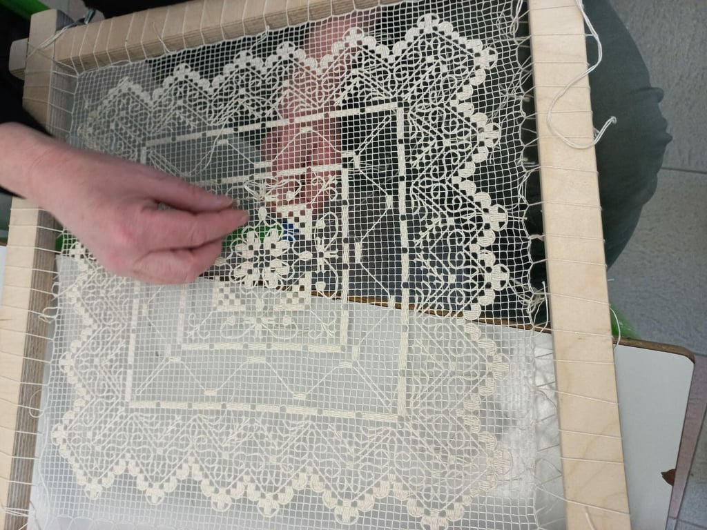 a person is holding a piece of lace and a needle