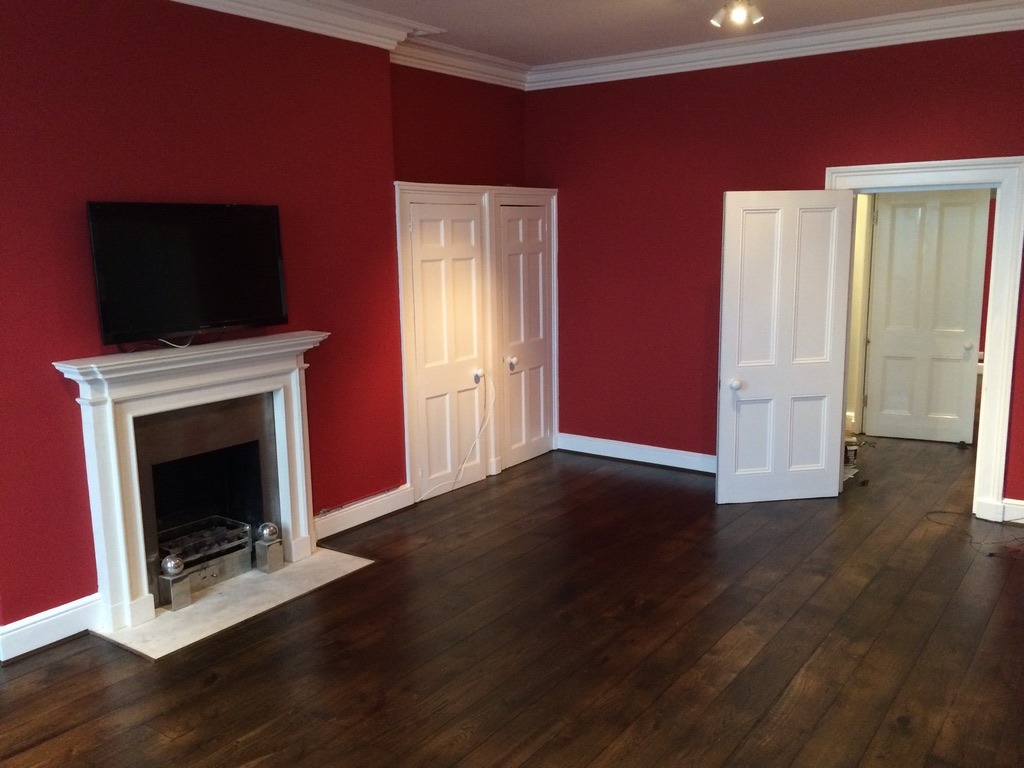 Brighton living room with bold red walls, white fireplace mantle, and matching white doors.