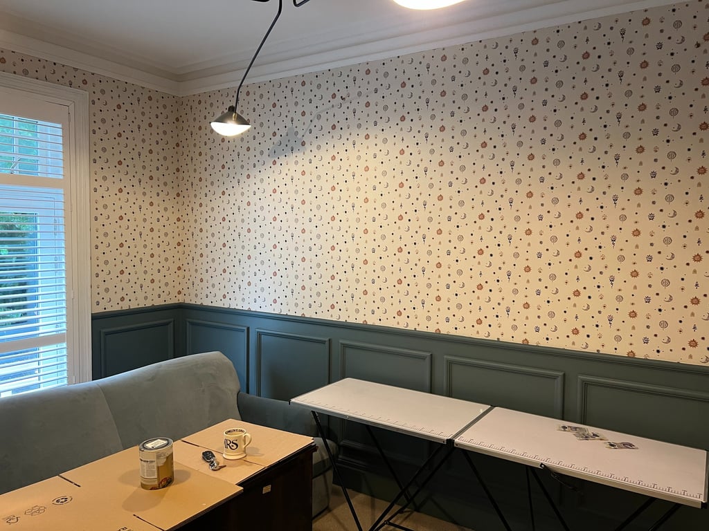 Room interior featuring celestial patterned wallpaper above dark teal board in East Sussex.